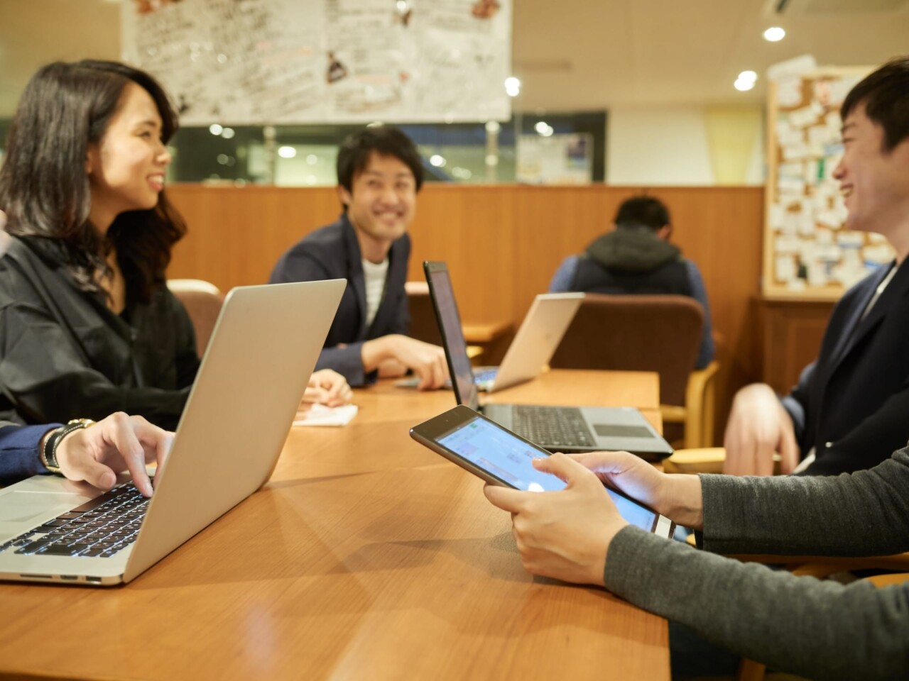 みんなでパソコンやタブレットを使って仕事をしている写真