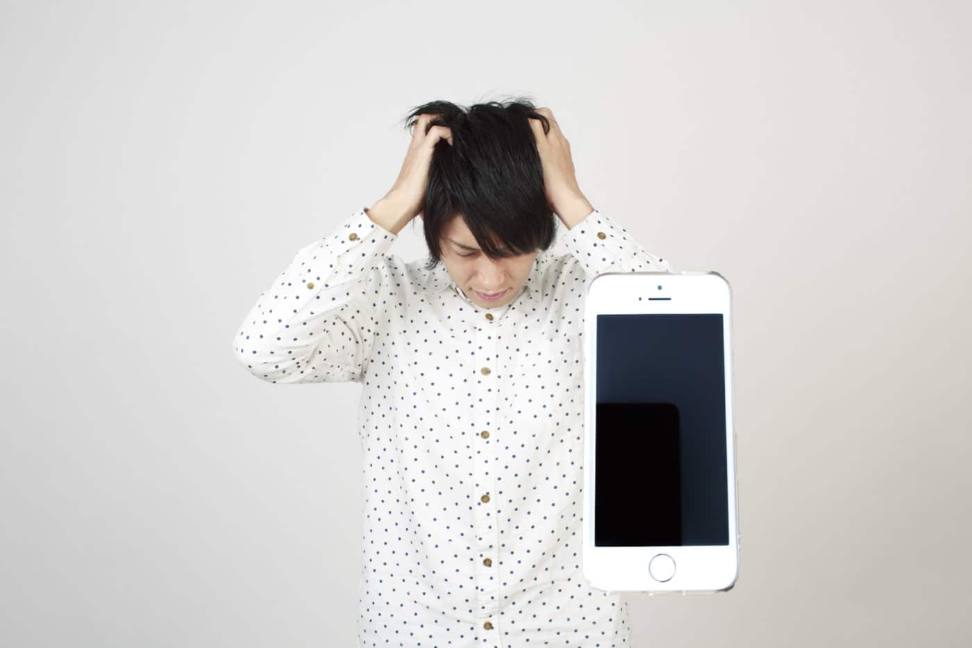 iPhoneで失敗して頭をかかえる男性